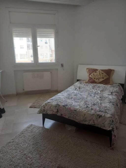 a bedroom with a bed and two windows and two rugs at Appartement plein Centre Urbain in Tunis