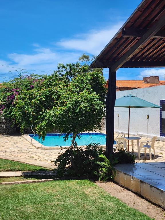 uma piscina com uma árvore e um guarda-sol em Casa na Ilha da Crôa em Barra de Santo Antônio