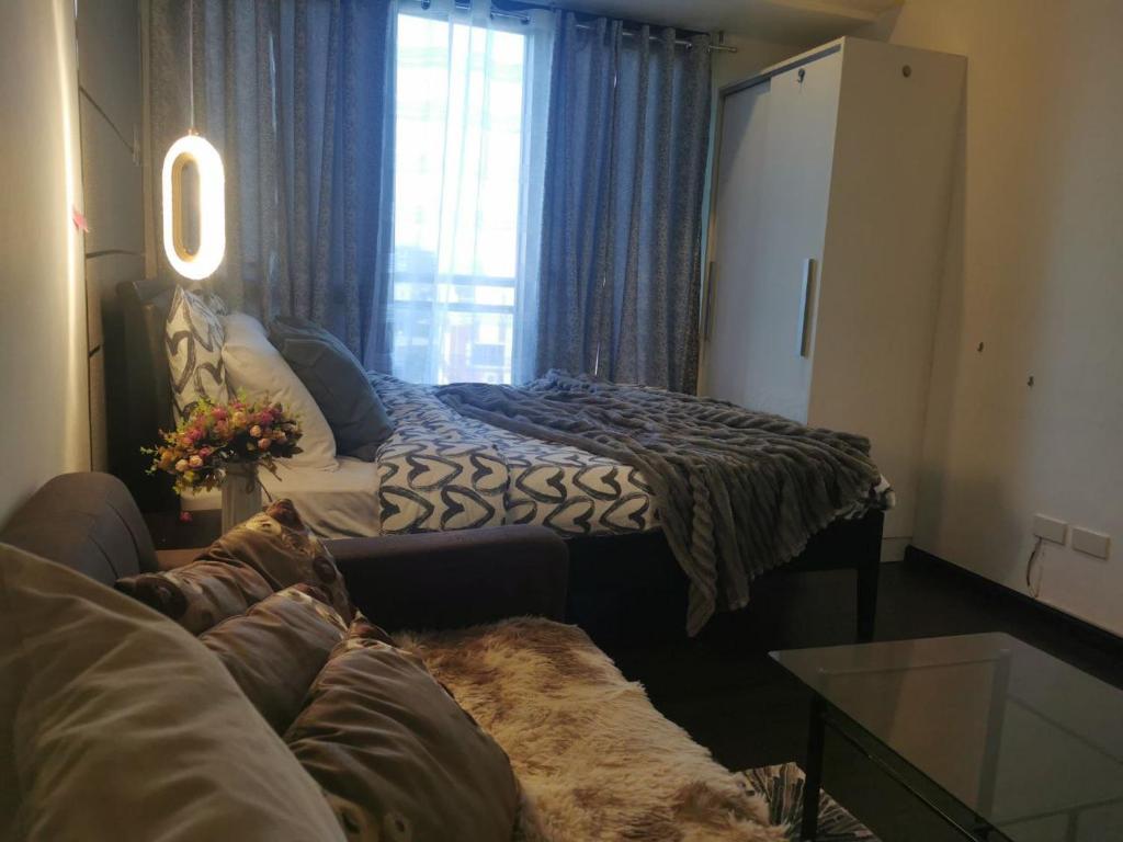 a room with a bed and a couch and a window at Elite Pod 5516 Knightsbridge Residences in Manila