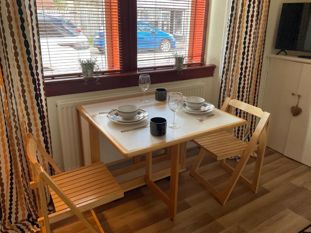 a table with two chairs and a table with wine glasses at Hillview, Ground floor apartment, Largs in Largs