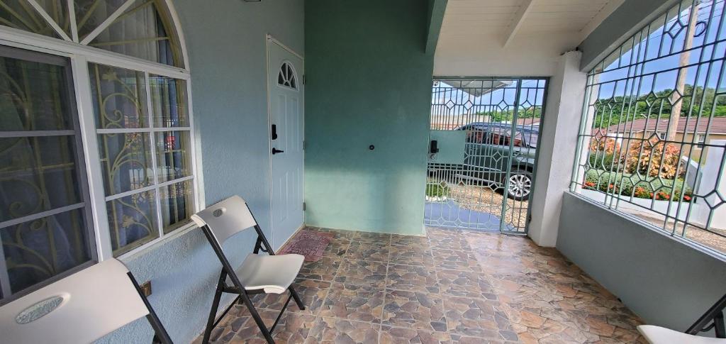 a room with two chairs and a hallway with windows at Hillside Retreat in Gated Community Close to Beach in Montego Bay
