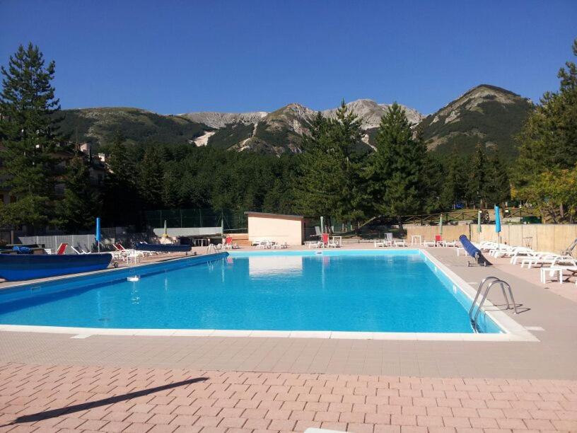 a large blue swimming pool with mountains in the background at Rifugio Luce in Ovindoli