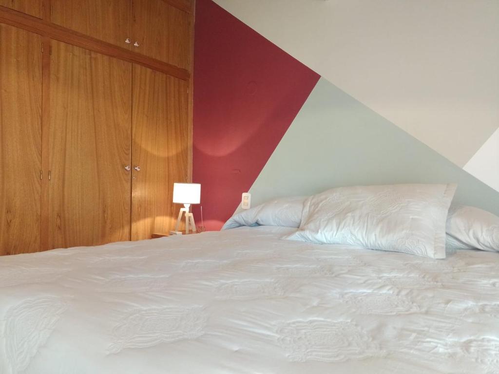 a bedroom with a large white bed with a red wall at 1780 Alojamiento in Guaymallen