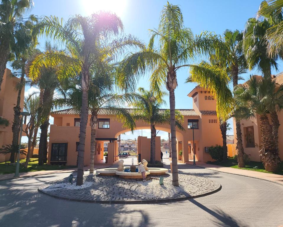a courtyard with palm trees in front of a building at Geweldig Appartement in Los Alcázares direct aan de Boulevard in Los Alcázares