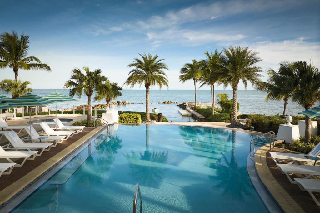 a large swimming pool with palm trees and the ocean at Courtyard by Marriott Faro Blanco Resort in Marathon