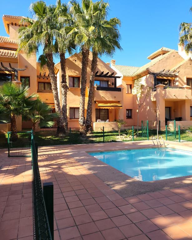 uma piscina em frente a um edifício com palmeiras em Geweldig Appartement in Los Alcázares direct aan de Boulevard em Los Alcázares