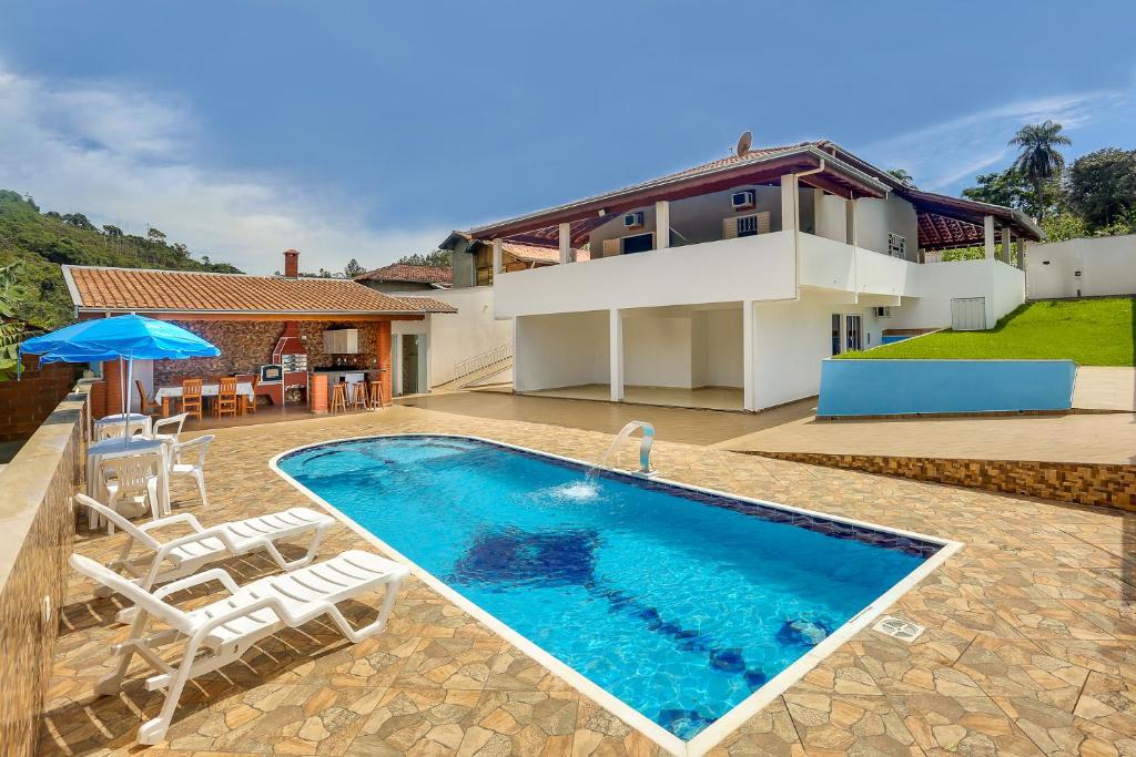 una piscina con sillas y una casa en Casa São Luis, en Lindóia