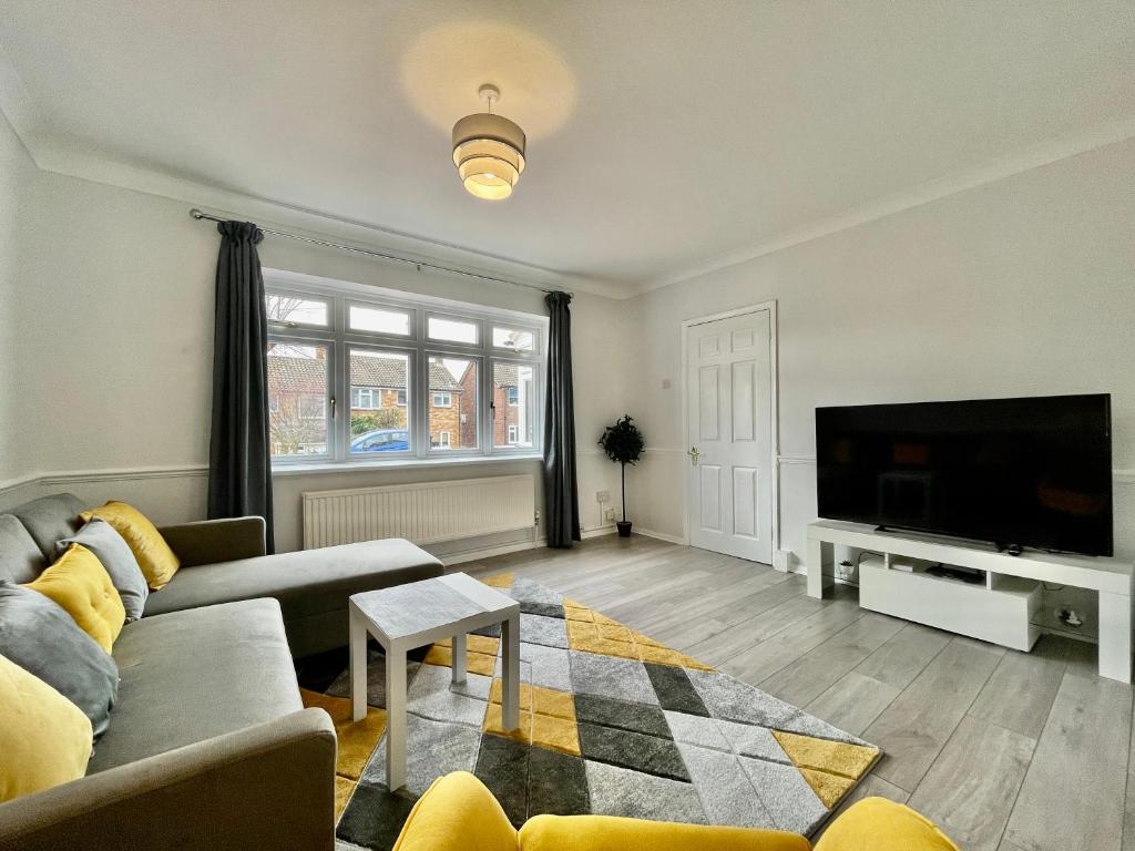 a living room with a couch and a flat screen tv at Modern 3 Bed Chigwell House (Free Parking) in Chigwell