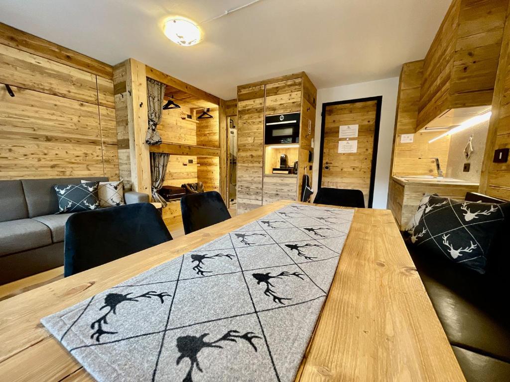 a room with a wooden table with chairs and a couch at Il Ruscello Mountain Apartment in Madesimo