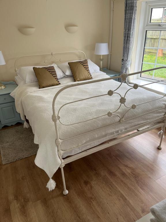 a white bed in a room with a window at Field Cottage in Whittlesey