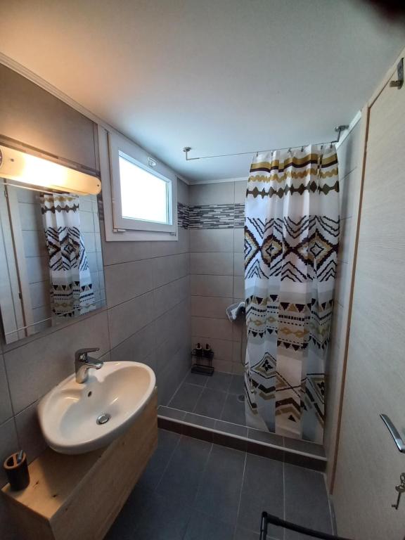 uma casa de banho com um lavatório e um chuveiro com uma cortina de chuveiro em A&D Central Apartment em Volos