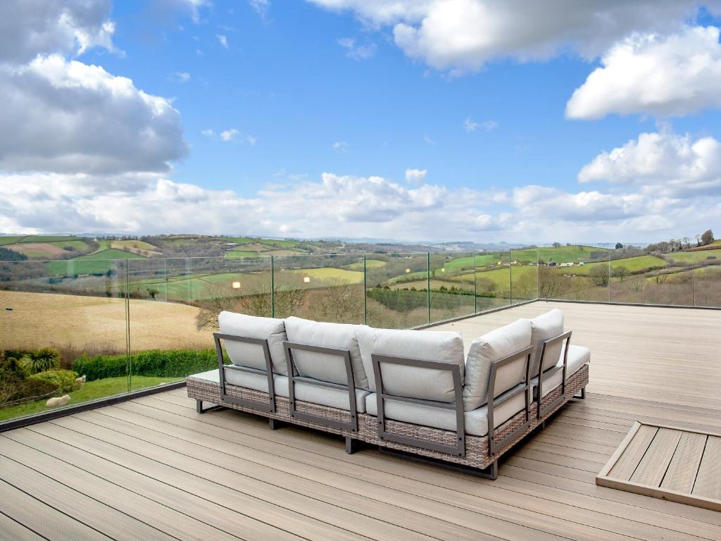 two white chairs on a deck with a view at Gratton House in Whitestone