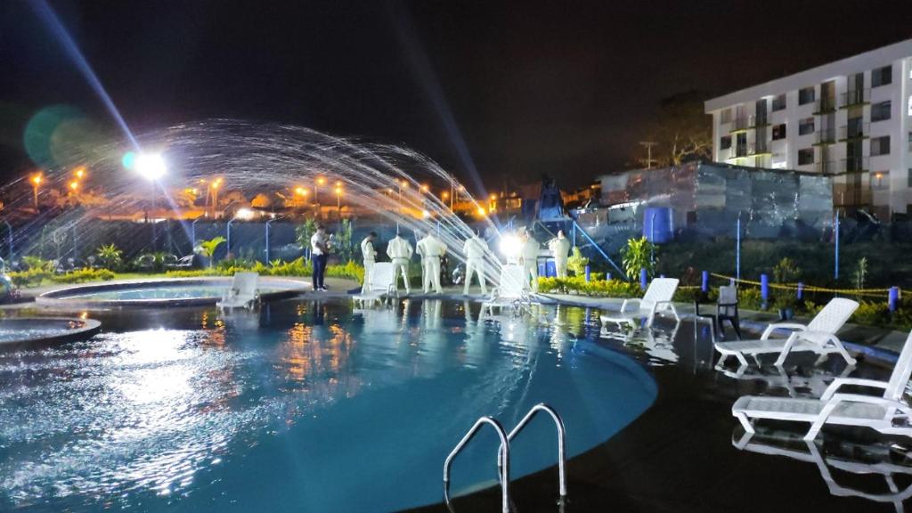 a pool at night with white chairs and a fountain at Apartamentos para tus vacaciones in Armenia