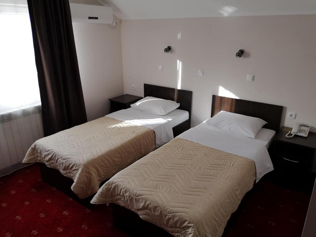 a hotel room with two beds and a window at Hotel Elegance in Belgrade