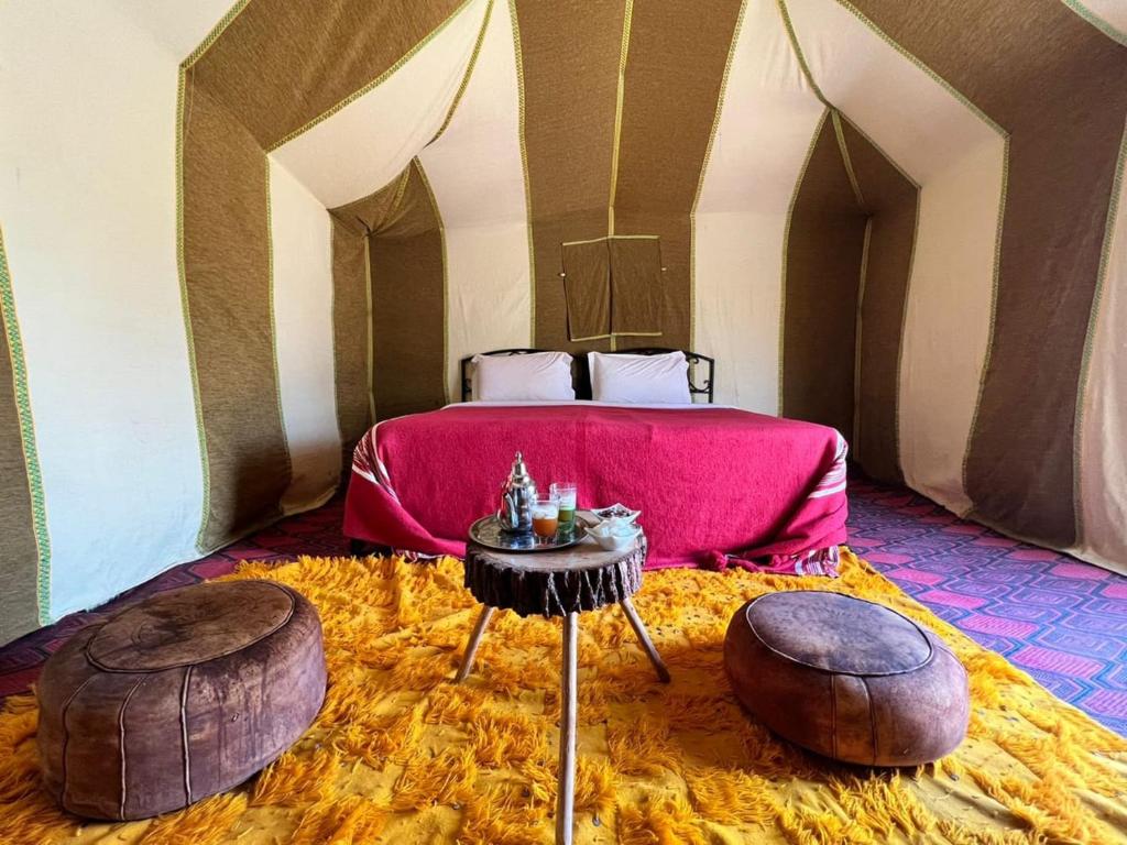 a bedroom with a bed and two ottomans at Merzouga Desert Campsite &Activities in Merzouga