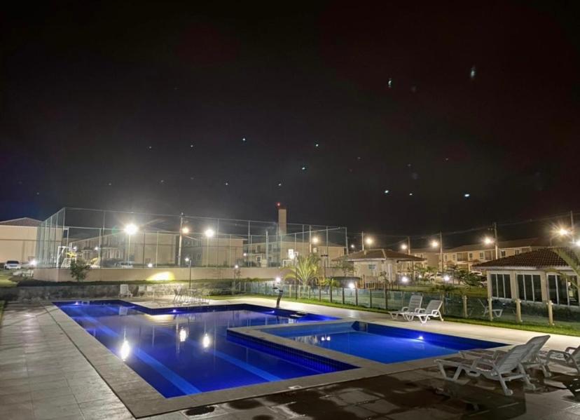 a swimming pool at night with lights on a building at Condomínio encantador in Caruaru