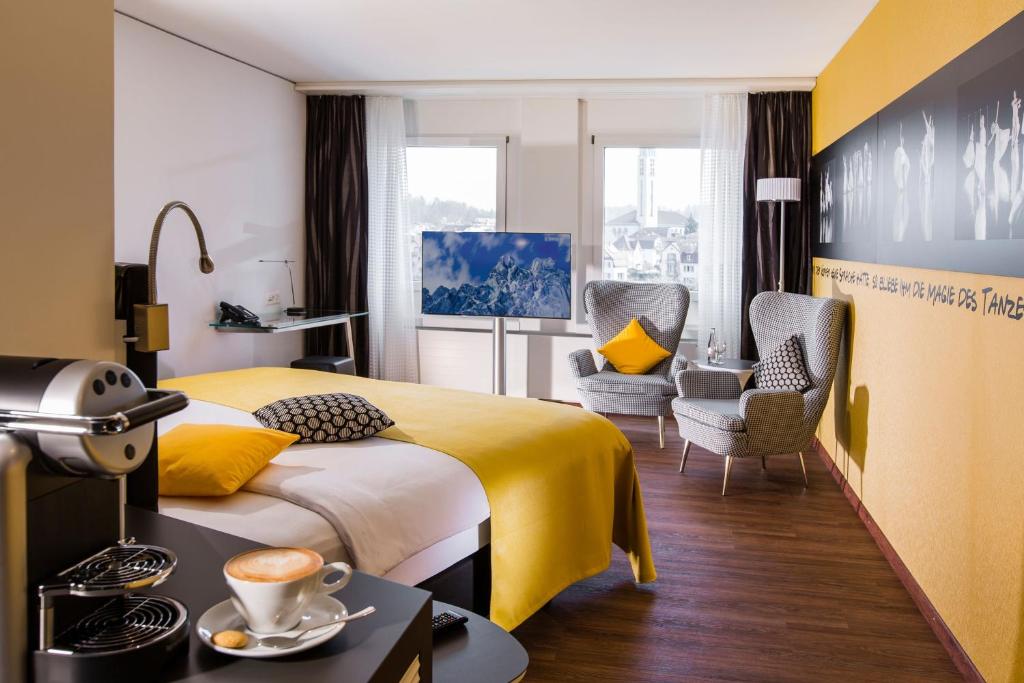 a hotel room with a yellow bed and a chair at Hotel Arte in Olten