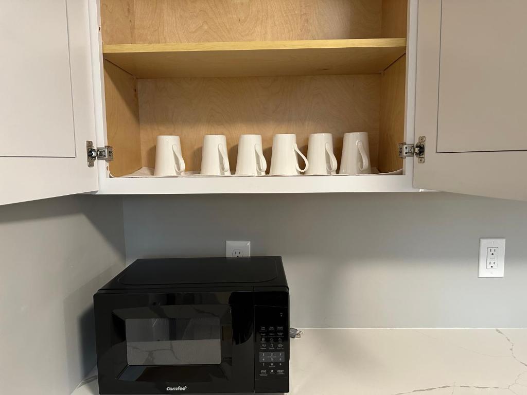un microondas negro en una cocina con armarios blancos en J2 Pleasant Queens Size room near St. Peter's hospital & New Brunswick Downtown en New Brunswick