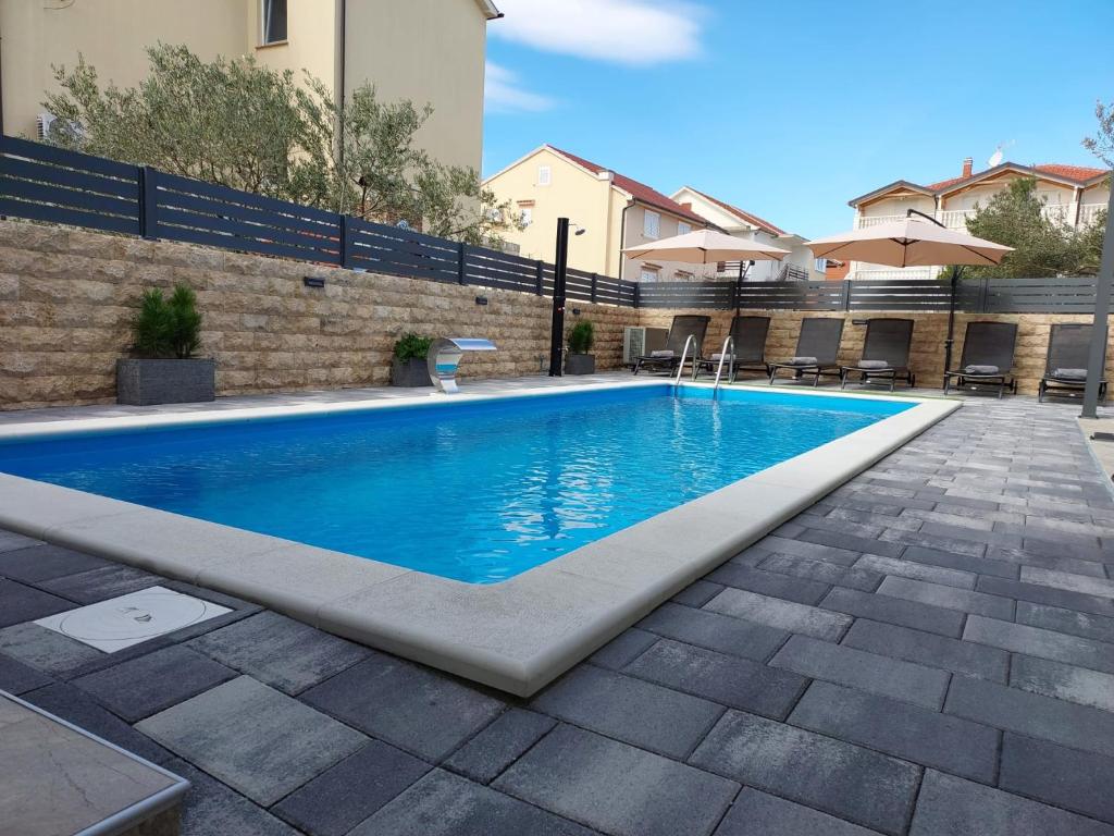 a swimming pool with blue water in a yard at Apartmani Tropical in Vodice