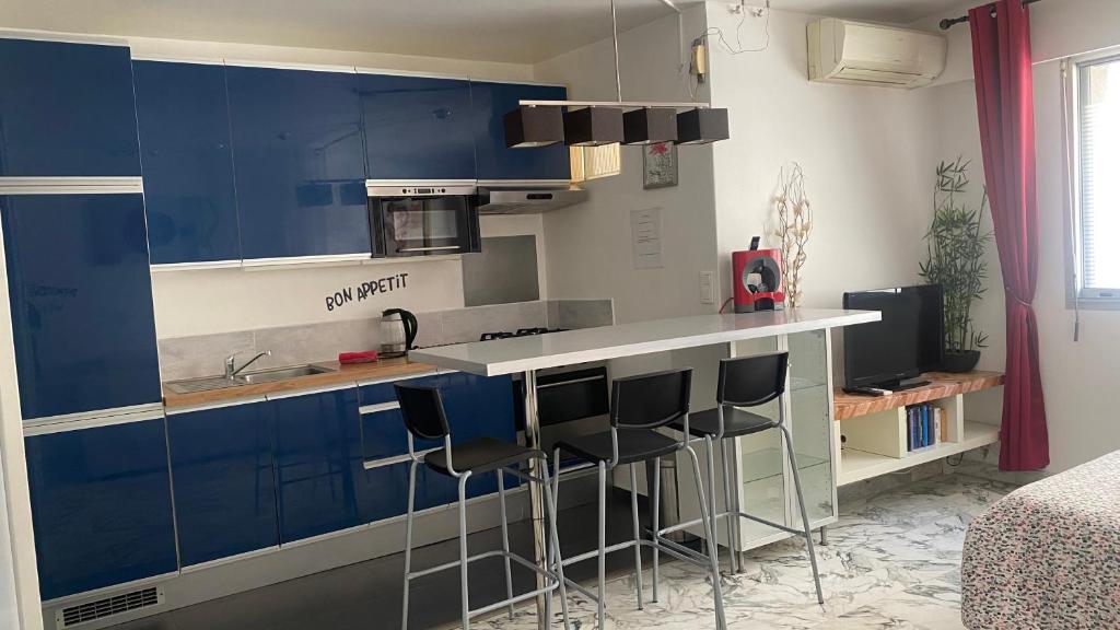 a kitchen with blue cabinets and bar stools at AZUR Studio 100 m des plages du Lido in Toulon