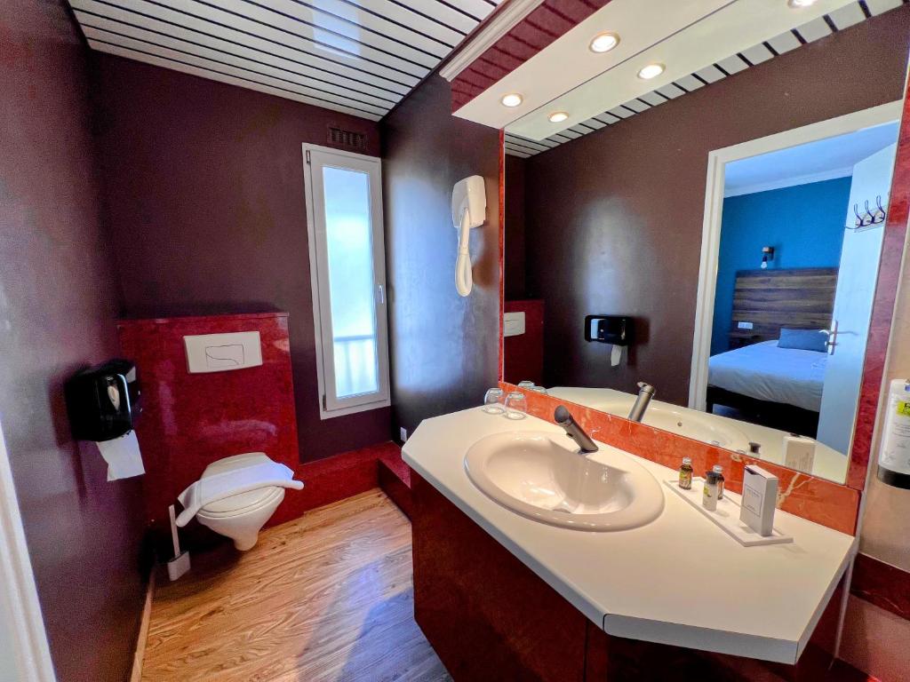 a bathroom with a sink and a toilet and a mirror at Logis Hôtel Spa la Poste in Vitry-le-François