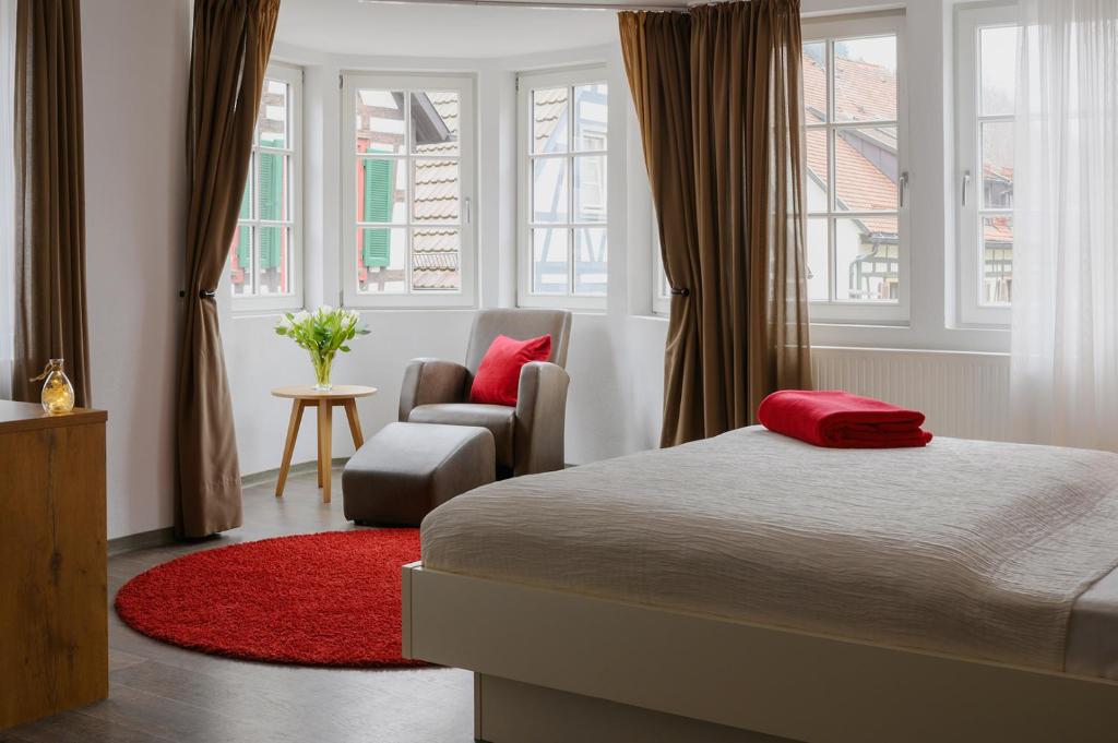 Schlafzimmer mit einem Bett, einem Stuhl und Fenstern in der Unterkunft Adler Schiltach Boutique Hotel und Restaurant in Schiltach