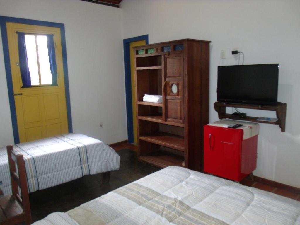 a bedroom with a bed and a television and a door at Pousada Ora Pro Nobis in Catas Altas