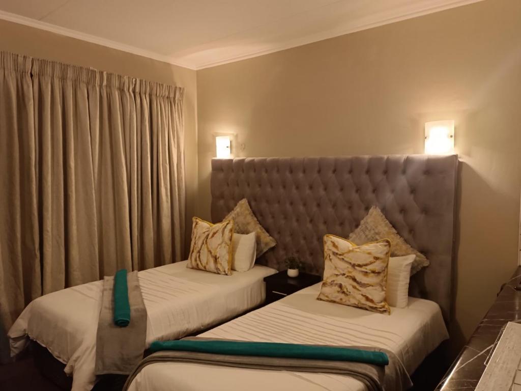 a hotel room with two beds and a headboard at Apartment A8 inside Bains Lodge in Bloemfontein