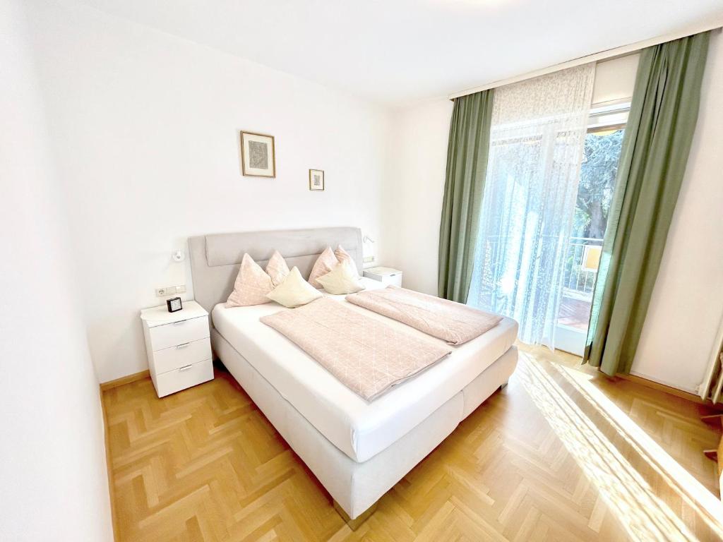 - une chambre avec un lit blanc et une grande fenêtre dans l'établissement Villa Sabine, à Merano