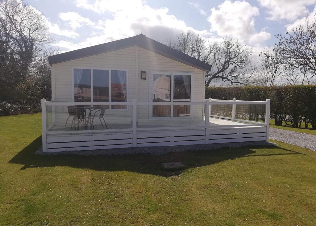 a small white house with a porch on the grass at Hamlet Rise in Leven