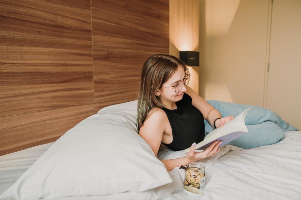 una mujer sentada en una cama leyendo un libro en Mercure Concepcion en Concepción