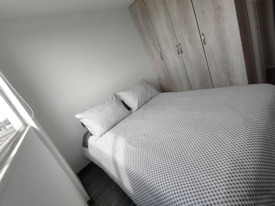 a small bedroom with a white bed with two pillows at Apartamento embajada americana in Bogotá