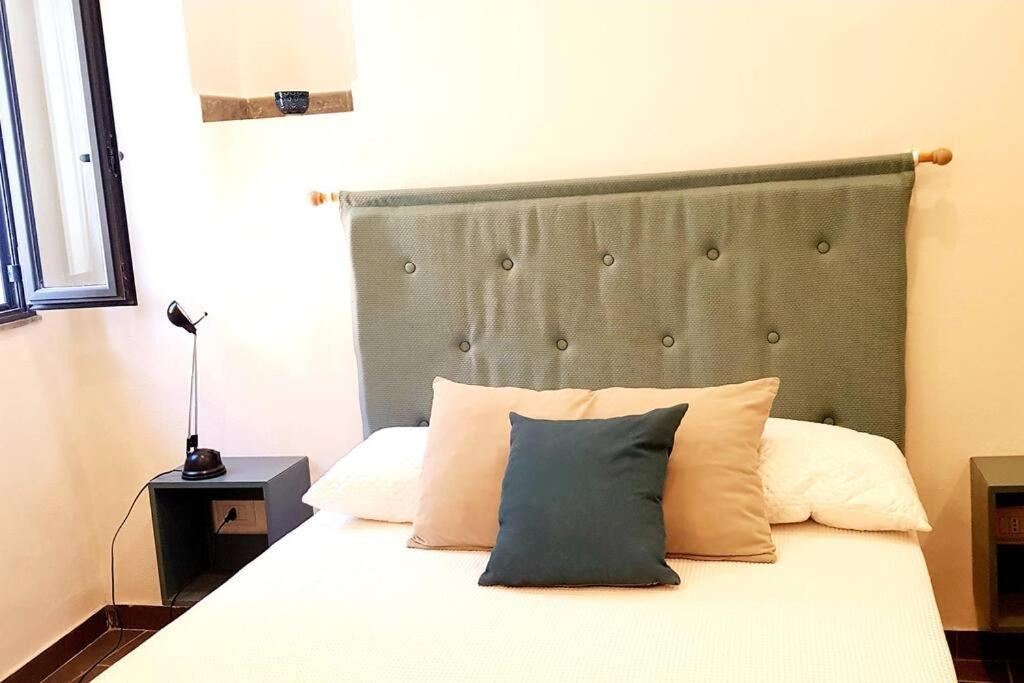 1 dormitorio con cama con cabecero gris y almohadas en L'Artista en Trecastagni
