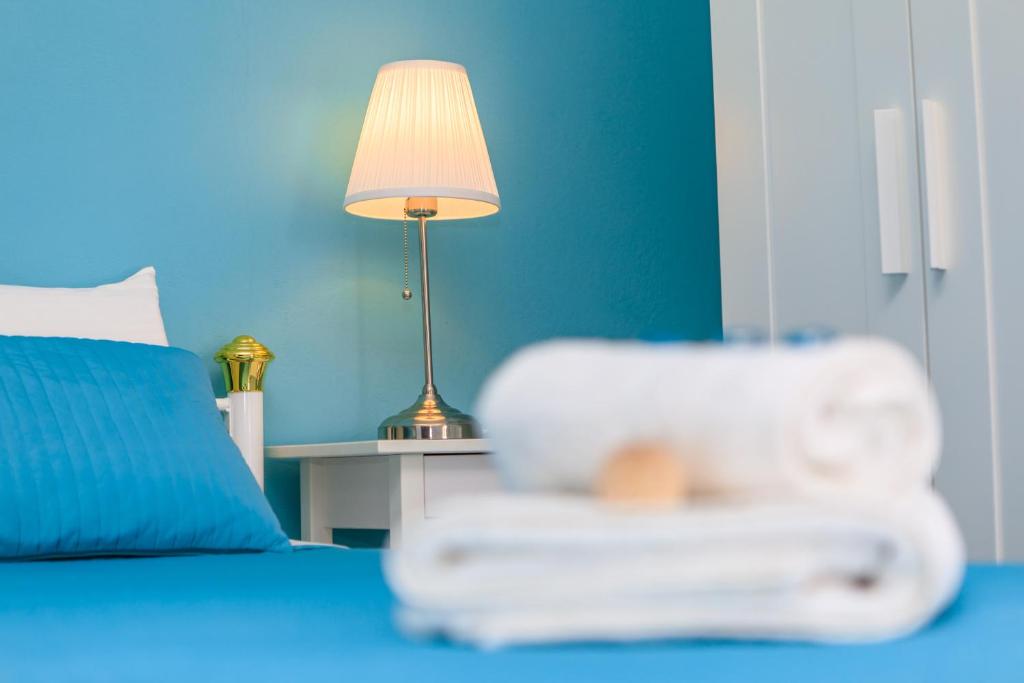 ein blaues Schlafzimmer mit einem Bett mit einer Lampe und einem Stuhl in der Unterkunft Maison Kalogiannis in Patitiri