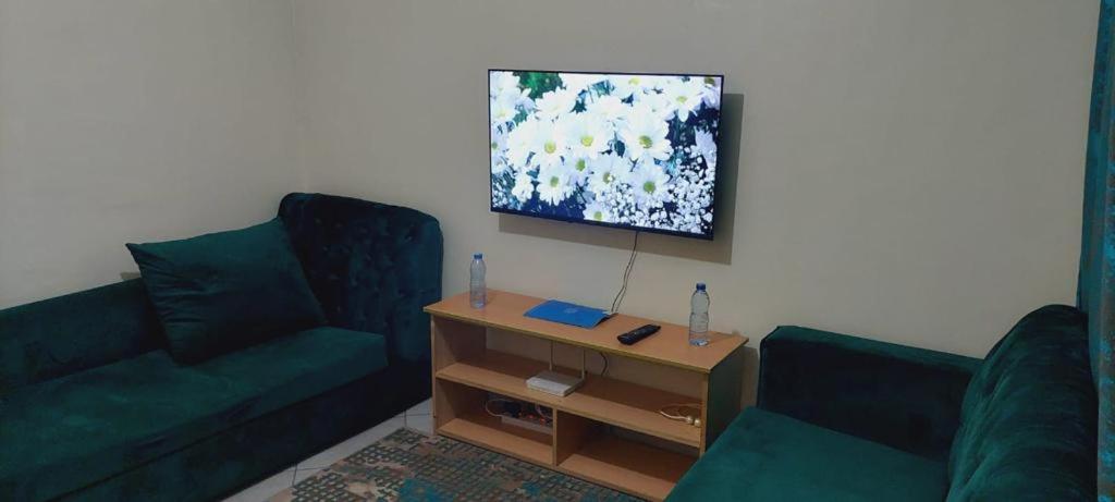 una sala de estar con 2 sofás verdes y una mesa. en Homes By Mwema en Nairobi