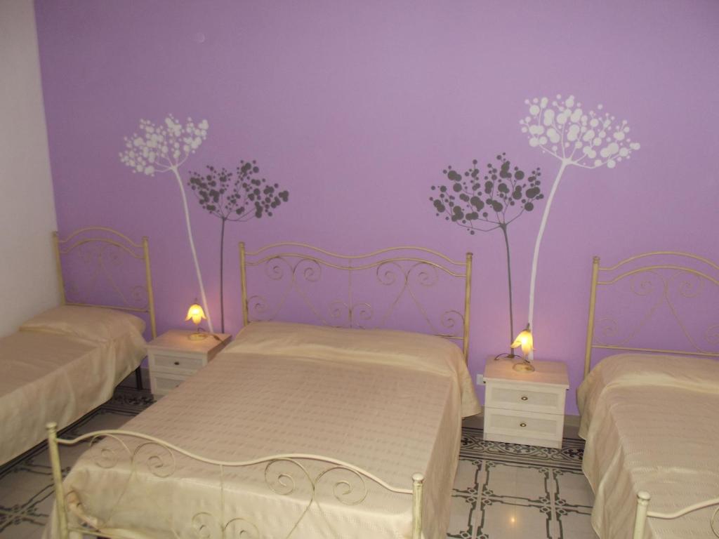two beds in a room with purple walls at La Dimora Siciliana in Trapani