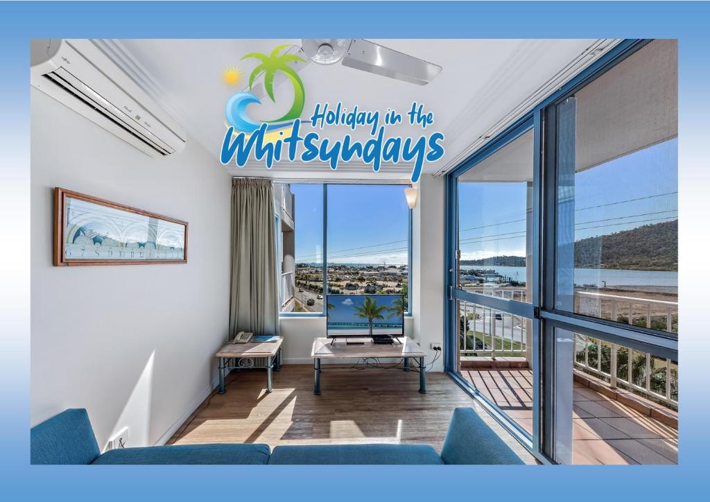 a living room with a sign that reads holiday to the wittaways at Marina views at Airlie 10H in Airlie Beach