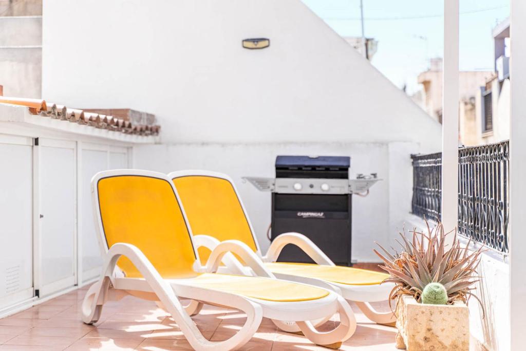 2 Stühle auf einem Balkon mit Herd in der Unterkunft Ático La Barca by Paradise Gold Rentals in Benidorm