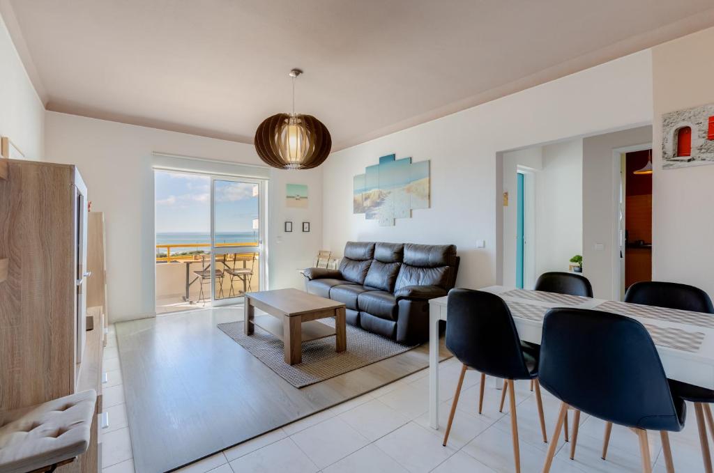 a living room with a table and chairs and a couch at Seafront 2 bedroom apart with air con and garage in Armação de Pera in Armação de Pêra