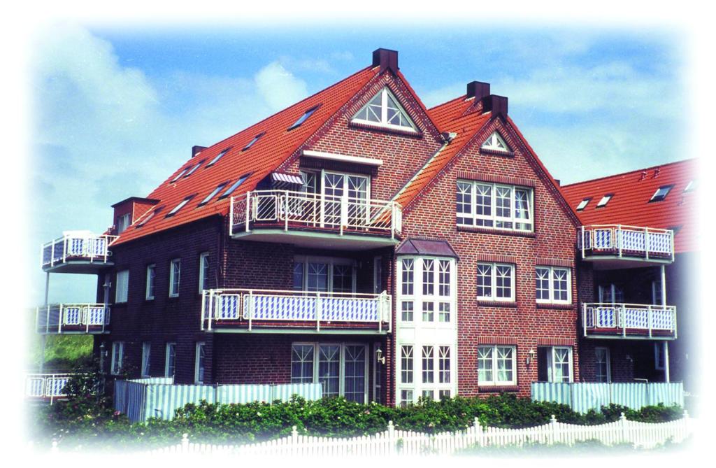a large brick building with a red roof at Juist - Freund, FeWo Inselresidenz Wattenmeer Wo3 in Juist