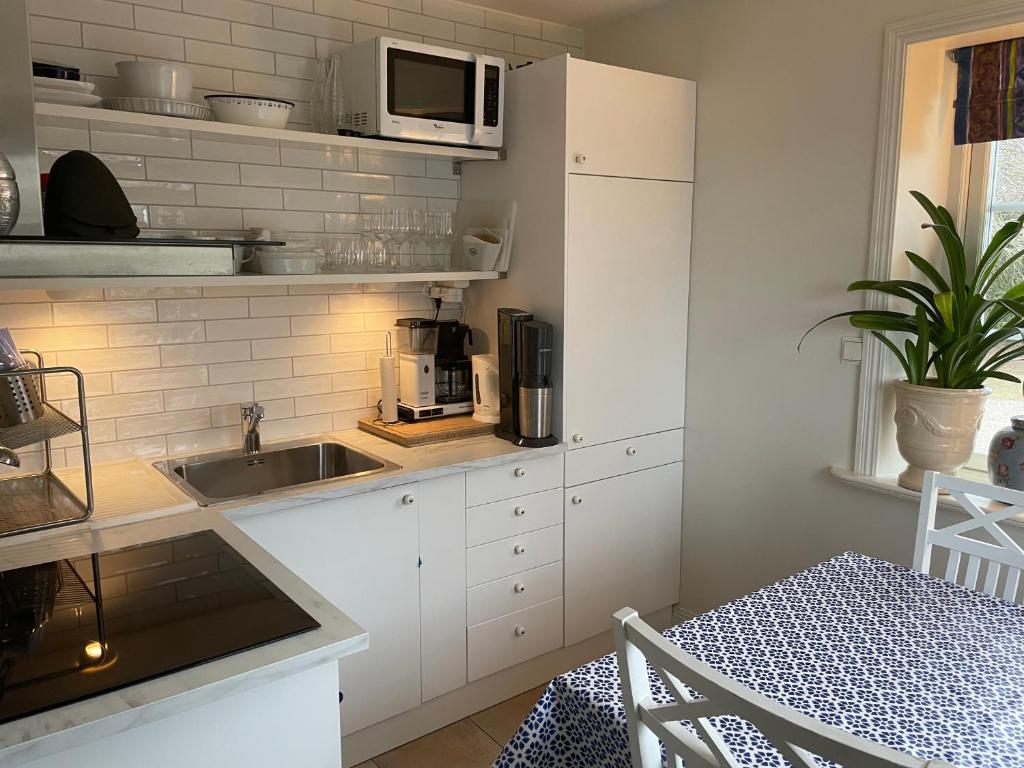 eine Küche mit einer Spüle und einer Mikrowelle in der Unterkunft Nyhamnsläge med sundsutsikt och nära till strand. in Nyhamnsläge