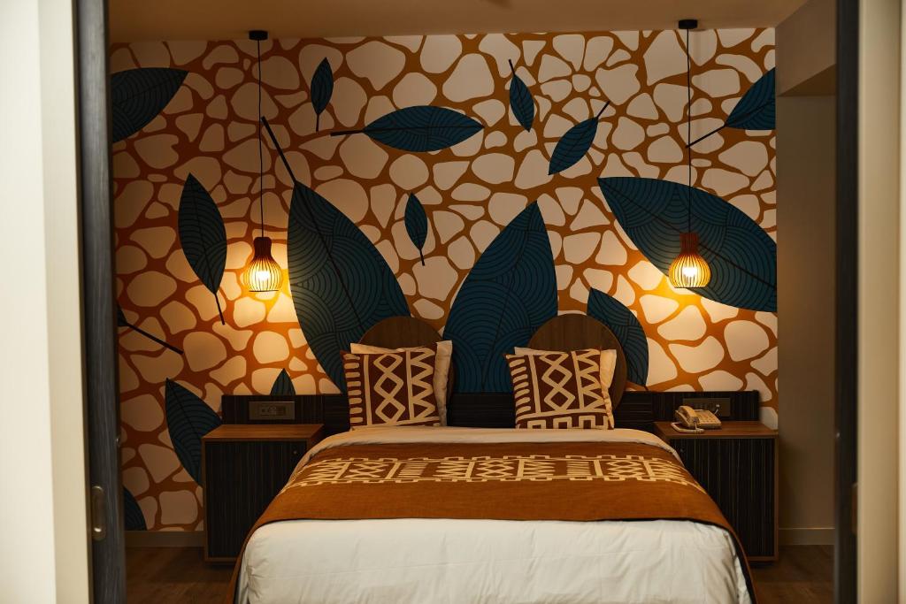 a bedroom with a bed and a wall with leaves at ONOMO Hotel Abidjan in Abidjan
