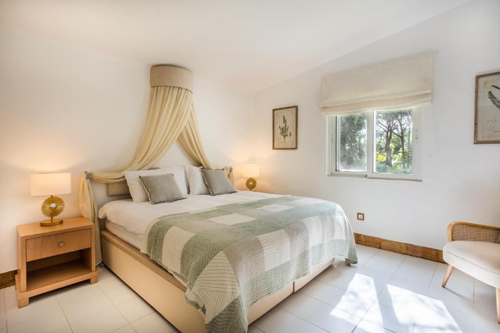 een witte slaapkamer met een bed en een raam bij Maria Lisboa in Almancil