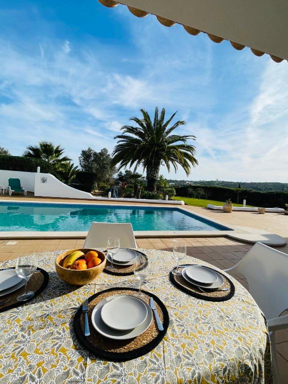 a table with a bowl of fruit and a laptop on it at Villa Serro das Vinhas in Portimão