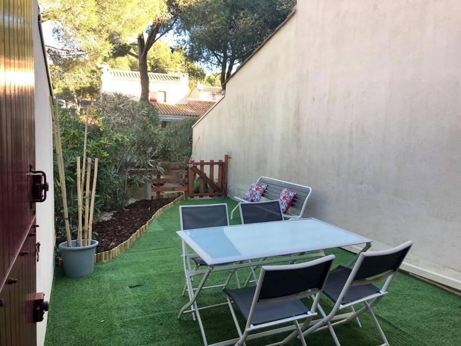 una mesa y sillas en un patio con césped en Joli appartement à proximité du village naturiste en Cap d'Agde