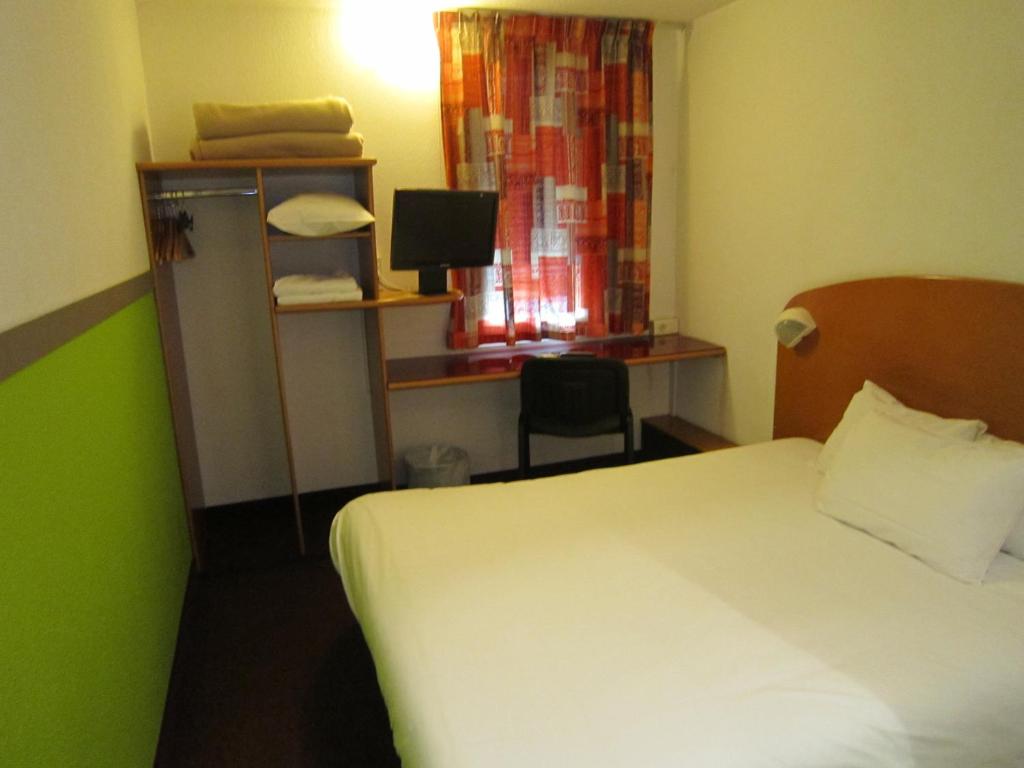 a hotel room with a bed and a desk and a window at Quick Palace Nantes La Beaujoire in Nantes