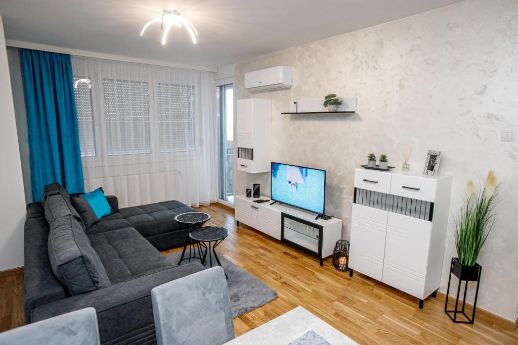 uma sala de estar com um sofá e uma televisão de ecrã plano em Tik Tak apartman em Subotica