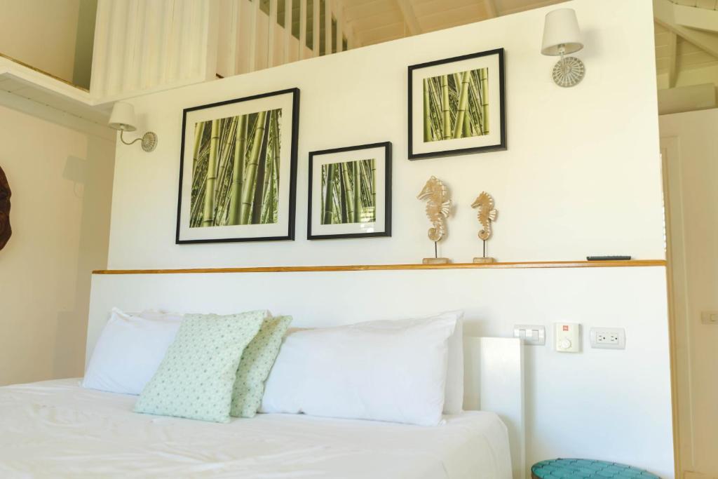 a bedroom with a white bed with three pictures on the wall at PUNTA POPY Boutique HOTEL in Las Terrenas