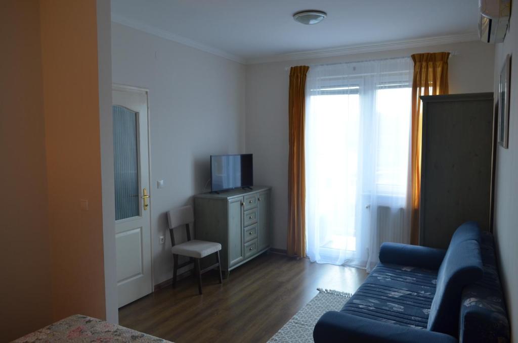 un soggiorno con divano blu e TV di Gabi Apartman a Hajdúszoboszló