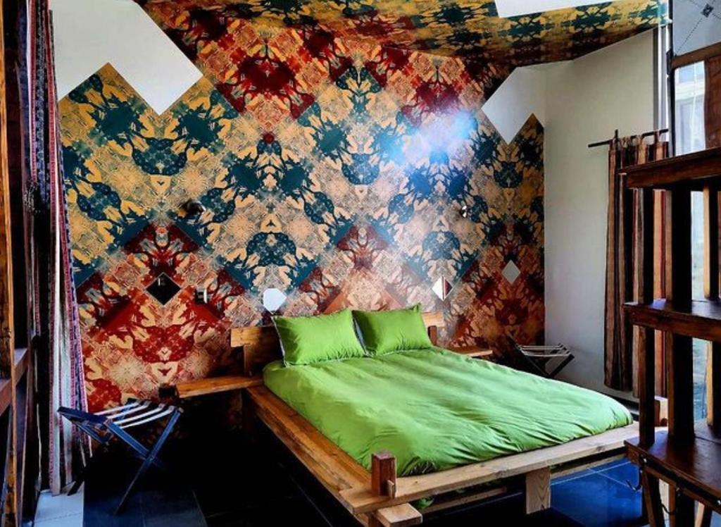 a bedroom with a green bed in front of a colorful wall at PazZHOtel in Valparaíso